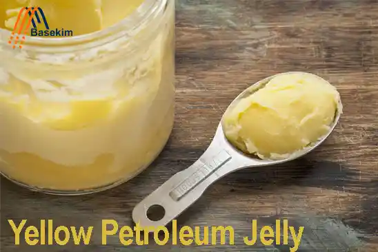 Yellow petroleum jelly in a jar with a spoonful on a wooden table – Basekim supplier UAE & Turkey.