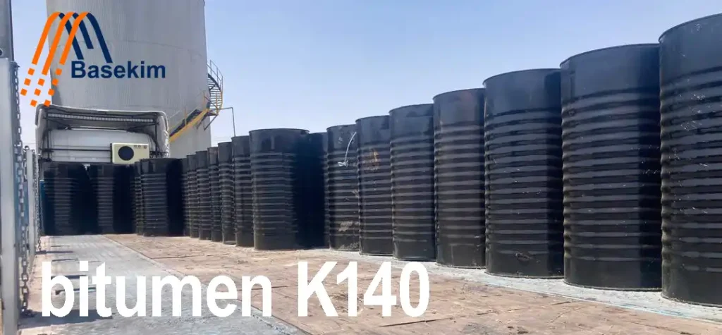 Black steel drums filled with Bitumen K140 lined up outdoors at a Basekim facility.