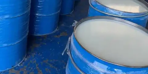 Rows of blue steel drums filled with refined petroleum jelly, ready for global shipment, featuring the Basekim logo on top of the image.