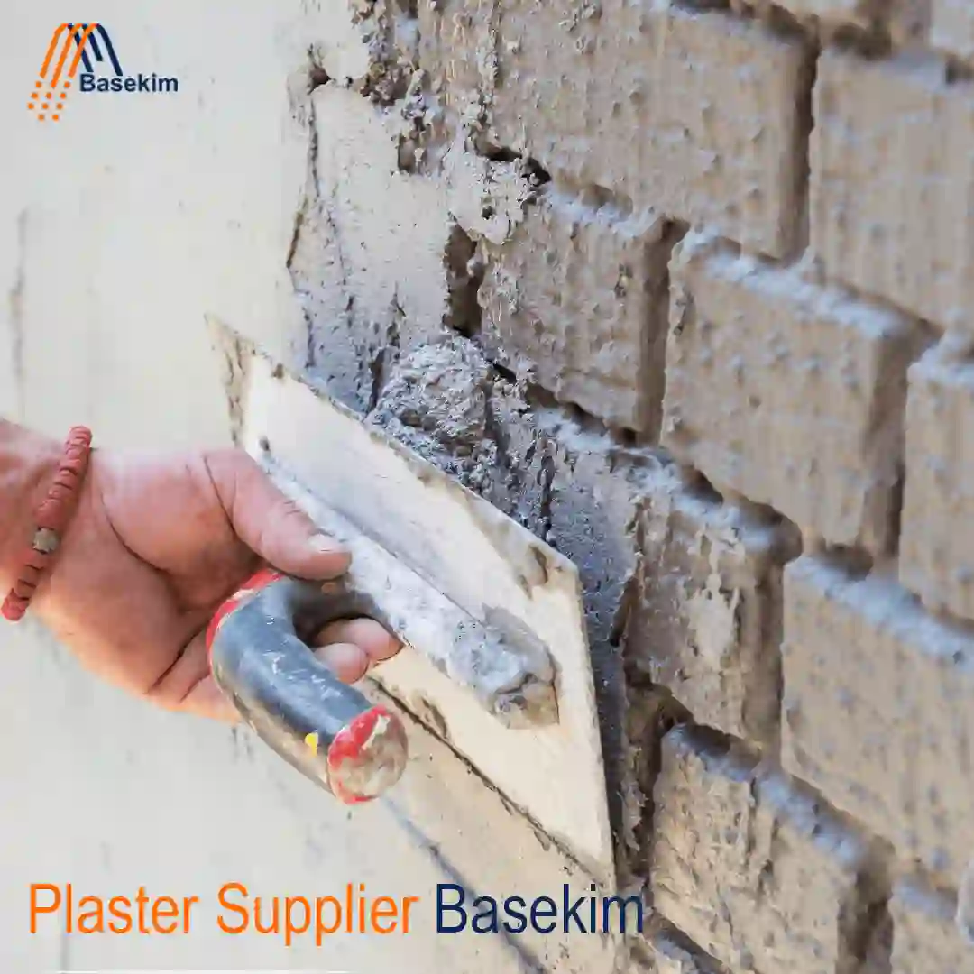Worker applying plaster to a brick wall using a trowel, supplied by Basekim.