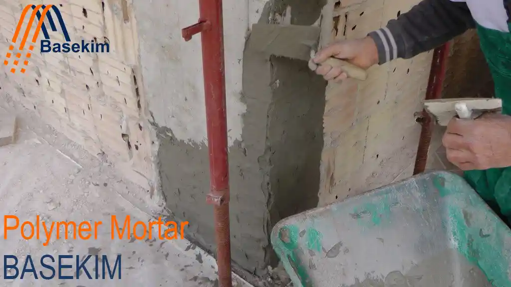 Worker applying polymer mortar to a brick wall using a trowel, supplied by Basekim.